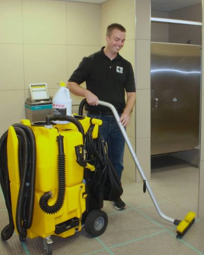 Jeffries Cleaning professional using machine to clean tile and grout in commercial bathroom