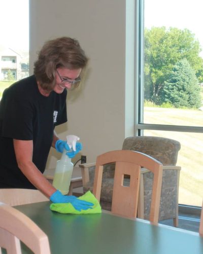 Jeffries professional using cleaning solution to wipe down tables and chairs
