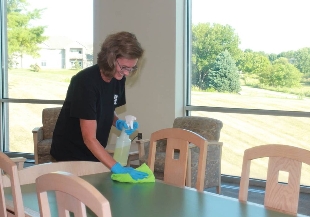 Jeffries professional using cleaning solution to wipe down tables and chairs